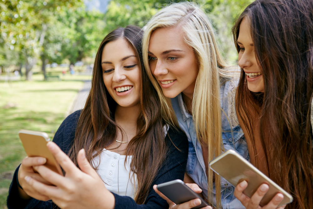 young friends watching viral social media video on mobile cell phone outdoors